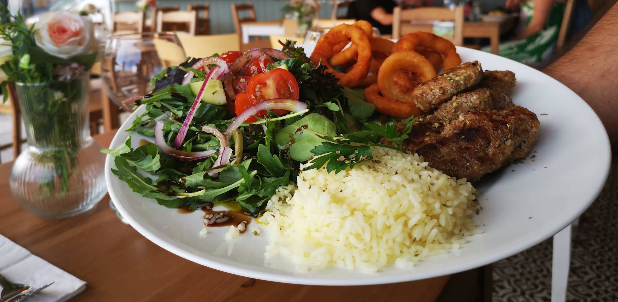 A complete white plate of food with rice, salad and browned pieces at Yaaze, with all edges of the plate visible